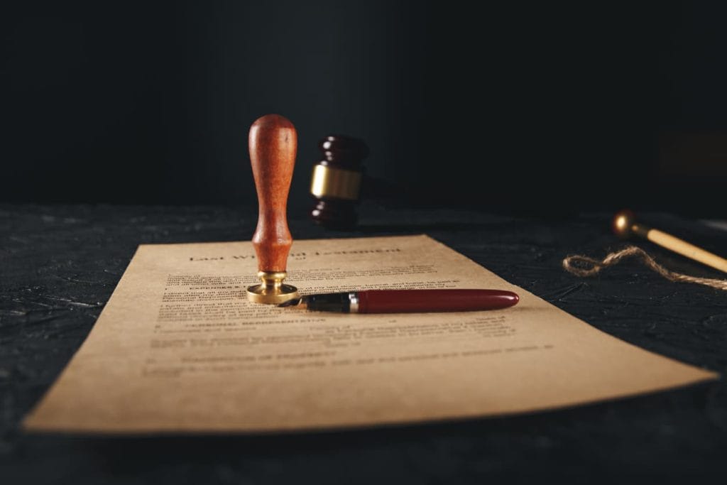 Protecting Your Assets: The Importance of a Properly Notarized Last Will and Testament 5 Last will and testament document with notary seal stamp and pen on a dark table, highlighting the importance of legal notarization for estate planning.