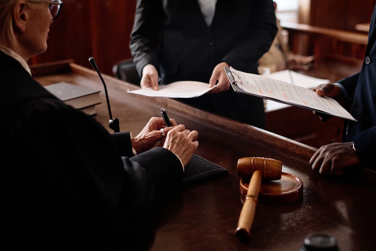 Close-up of a judge and legal professionals handling official court documents. Learn how to notarize and Apostille court papers with NotaryPublic24.