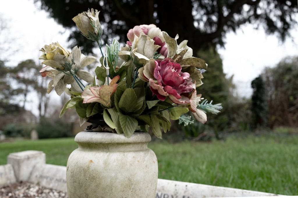 Artificial funeral flowers in a vase placed on a grave, representing remembrance and official cremation records — relevant to understanding cremation certificates and their notarization or Apostille requirements for international use