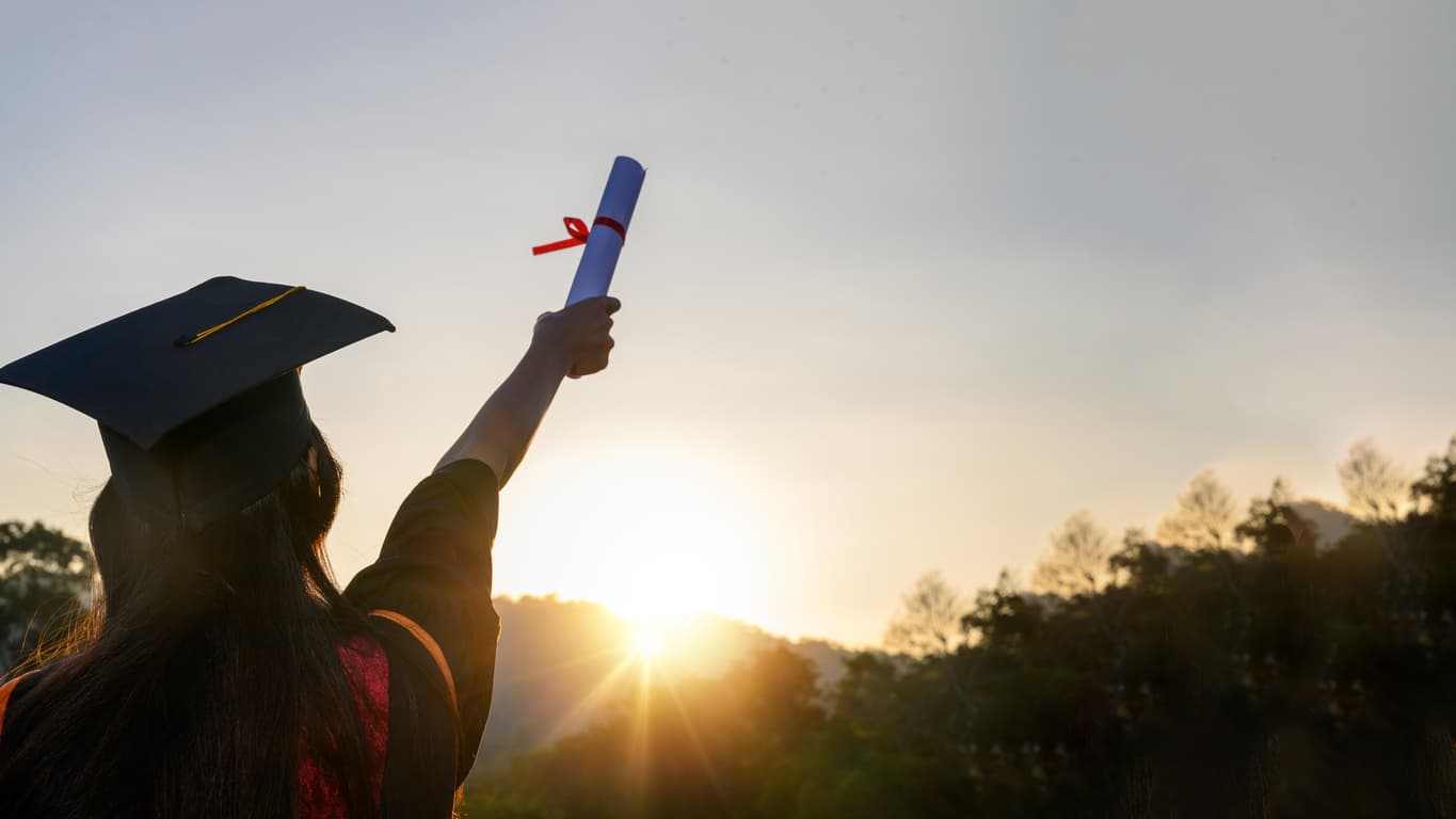 Graduate holding educational certificate at sunrise, symbolizing global recognition through notarization, Apostille and verification of academic credentials